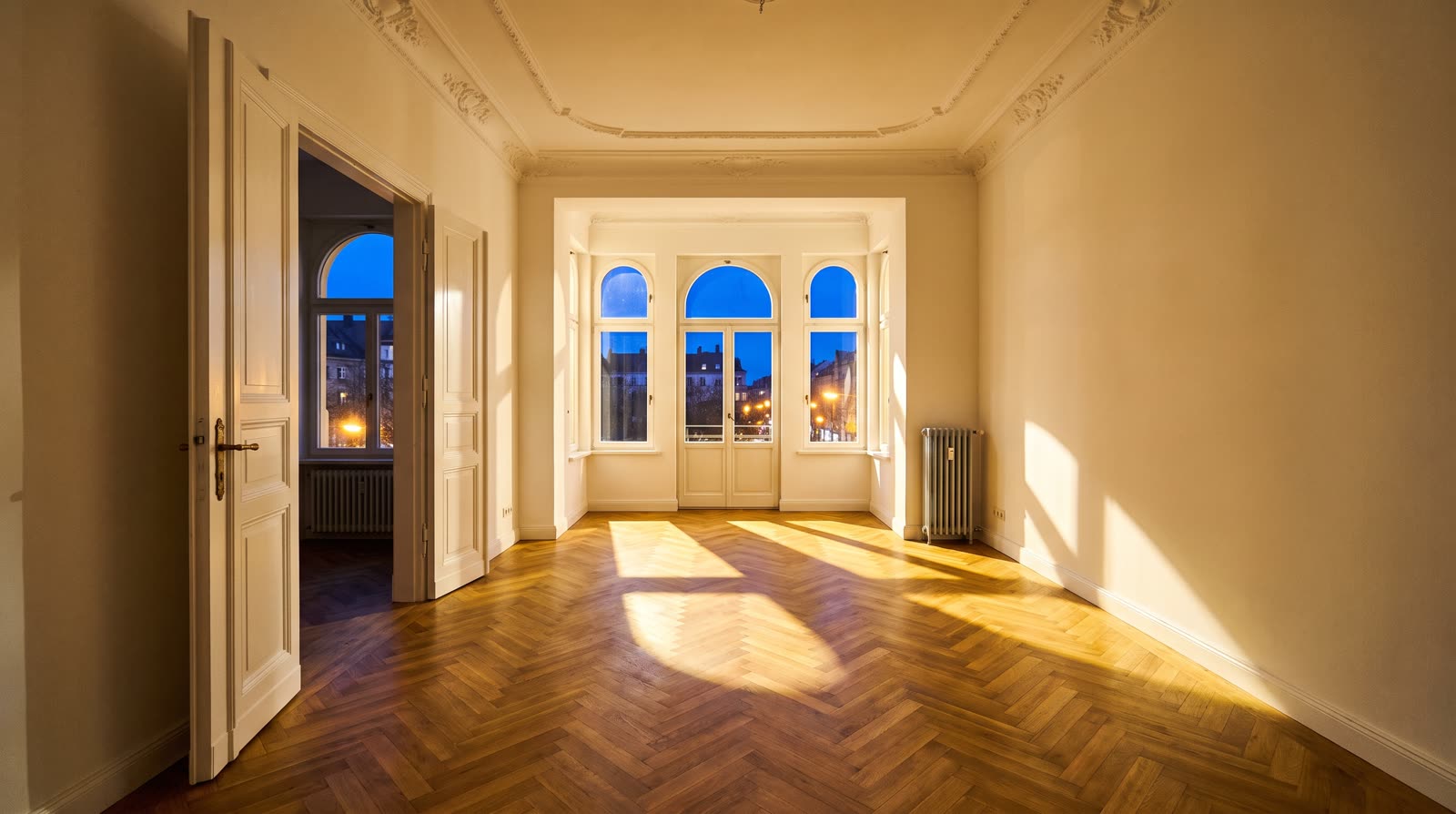 Heller Altbau-Innenraum mit Fischgrätparkett im Abendlicht